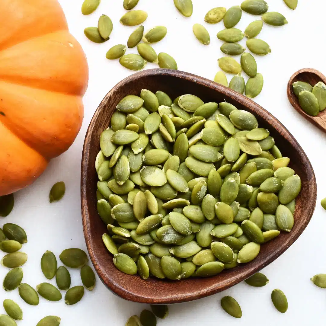 Just Shudh Pumpkin Seeds (Kaddu ke Beej) | Raw & Natural | 30g Protein per 100g | Rich in Zinc & Magnesium | Supports Immunity, Heart Health & Muscle Recovery | No Additives 3 fresh green pumpkin seeds in wooden bowl closeup with whole pumpkin